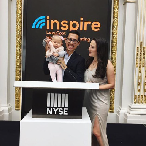 Robby Valderrama with Bria and their daughter at the New York Stock Exchange, in front of an Inspire Investing banner
